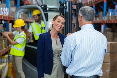 A part time finance director standing in a warehouse talking to a business owner